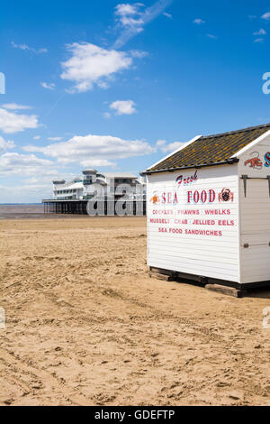 Un étal de fruits de mer sur la plage de Weston-super-Mare avec le Grand Pier derrière, North Somerset, Angleterre. Banque D'Images