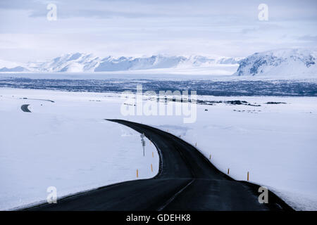 Route sinueuse à travers la neige paysage d'hiver, l'islande Banque D'Images