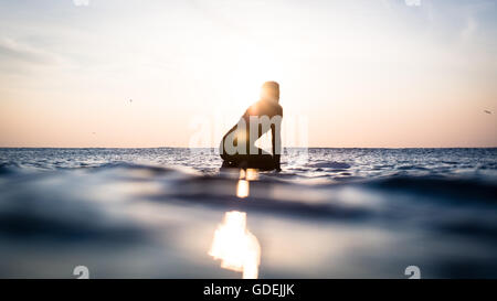 Silhouette d'une femme assise sur une planche de surf dans l'océan, Malibu, Californie, Amérique, USA Banque D'Images