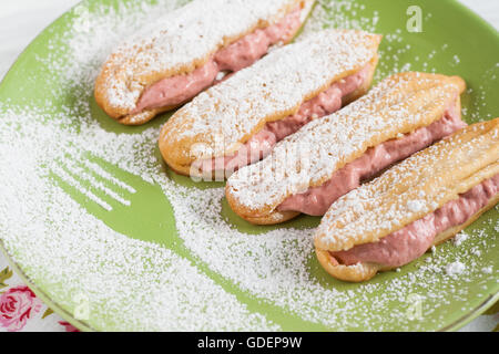 Éclairs à la crème de fraises framboises et sucre en poudre. Banque D'Images