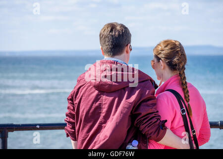 Un jeune homme et femme regardant la mer d'un port. Banque D'Images