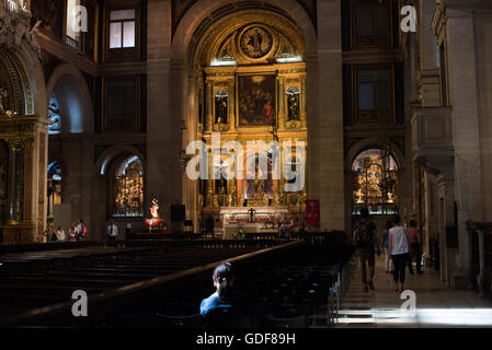 Igreja de Sao Roque Nef Unique Intérieur Visiteurs Lisbonne Portugal | LISBONNE, Portugal — Les visiteurs avancent dans la large nef unique de l'Igreja de São Roque, l'ancienne église jésuite de Lisbonne, son retable principal doré brillant à l'extrémité et des chapelles latérales richement décorées s'ouvrant sur les deux murs. L'architecte Filippo Terzi a conçu la nef vers 1565 comme une «église auditorium» – une vaste salle sans allées – afin qu'une assemblée puisse entendre le prédicateur jésuite depuis n'importe quel siège, un plan qui est devenu l'un des modèles décisifs de l'architecture religieuse de la Contre-Reforme. L'église a traversé Banque D'Images