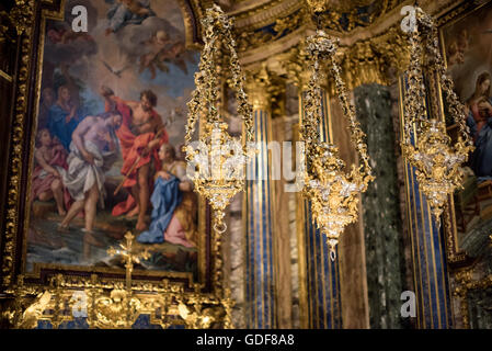 Igreja de Sao Roque Chapelle Saint-Jean-Baptiste Lanternes dorées Lisbonne Portugal | LISBON, Portugal — Des lanternes suspendues en or et argent flottent devant un retable peint dans la Chapelle de Saint-Jean-Baptiste (Capela de São João Baptista) à l’Igreja de São Roque, ses colonnes veinées de bleu — parmi les incrustations de pierre précieuses de la chapelle — encadrant la composition. Commandée par le roi João V, construite à Rome entre environ 1742 et 1747 par les architectes Nicola Salvi et Luigi Vanvitelli utilisant du lapis-lazuli, de l’agate, de l’améthyste, de l’albâtre et du porphyre, elle a été bénie par le pape Benoît XIV et expédiée à Lisbonne sur trois ve Banque D'Images