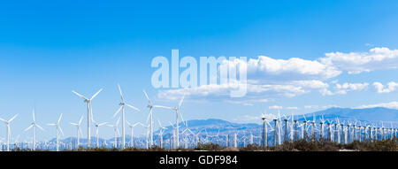 Panoramique horizontal tourné d'un champ d'éoliennes against a blue sky Banque D'Images