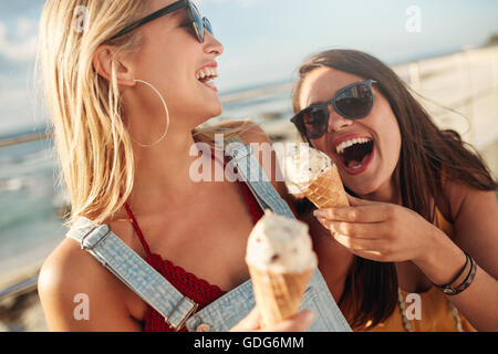 Deux meilleurs amis, pour avoir ensemble la crème glacée à l'extérieur. Close up of young women eating icecream et rire. Banque D'Images