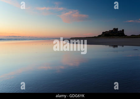 Pastle subtils tons dans le ciel au-dessus de château de Bamburgh, reflétée sur la plage humide, Northumberland, England Banque D'Images