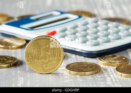 Pièces en euros et calculatrice numérique gris sur fond de bois Banque D'Images