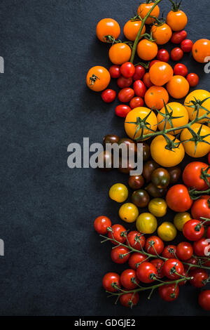 Sélection de tomates multicolores, fond frontière ardoise foncé Banque D'Images