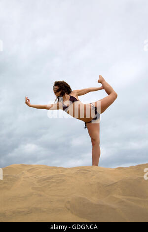 Jeune femme pratiquant le yoga dans le désert de sable Banque D'Images