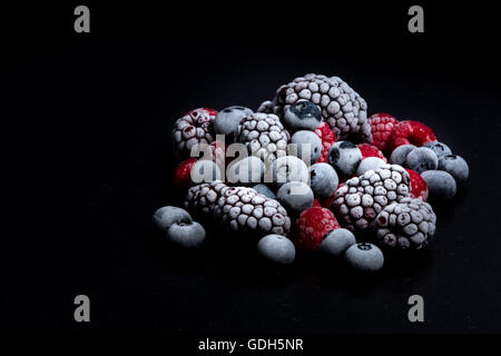 Les fruits des bois, framboises, bleuets et mûres sur une table en pierre noire Banque D'Images