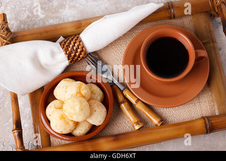 Snack-brésilien Pao de Queijo" (pain au fromage) sur la plaque brune avec une tasse de café sur le bambou bac. Selective focus Banque D'Images