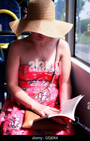 Woman in hat lecture ebook sur train bus Banque D'Images