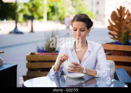 Jeune femme moderne assis dans un café et d'attendre que quelqu'un à la recherche de montres sa Banque D'Images