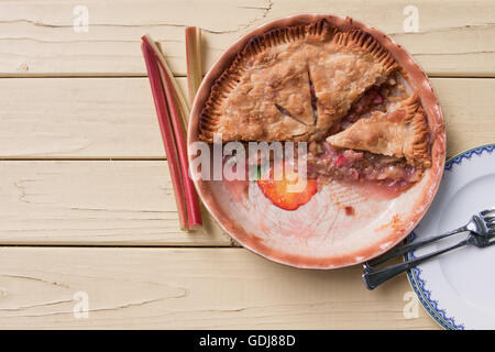 Tarte à la rhubarbe fraîchement cuit, tranché et prêt à servir sur table jaune - Vue de dessus Banque D'Images