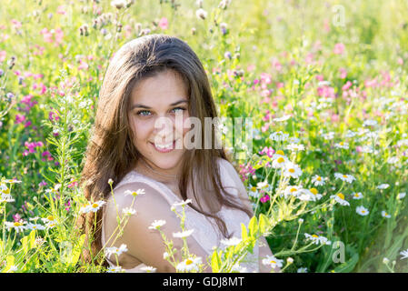 Belle jeune fille aux cheveux longs sur glade avec prairie, fleurs Banque D'Images