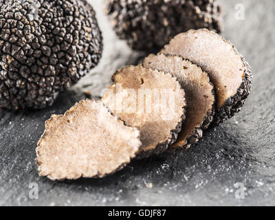 Truffes noires et truffes tranches sur le conseil de graphite. Banque D'Images