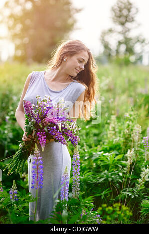 Belle femme avec bouquet de fleurs sauvages dans la prairie Banque D'Images