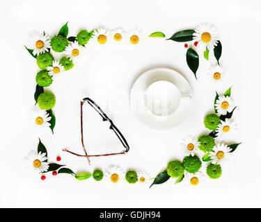 Tasse de café ou de thé et des verres avec floral frame à partir de camomille et de fleurs de chrysanthème, ficus feuilles et ripe rowan sur whi Banque D'Images