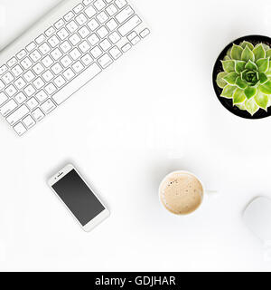 Table de bureau blanc sans fil avec clavier en aluminium, tasse de café, téléphone intelligent avec écran noir, souris et succulentes rose ... Banque D'Images