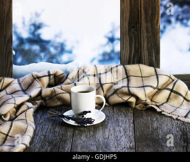 White tasse de café ou de thé, fleurs de lavande et plaid laine situé sur un rebord de fenêtre en bois stylisés. Notions de confort d'hiver Banque D'Images