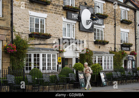 L'extérieur de l'établissement Black Swan Hotel, Helmsley, North Yorkshire - 1 dame marcher passé popular boutique hotel dans le centre historique de la ville de marché. Banque D'Images