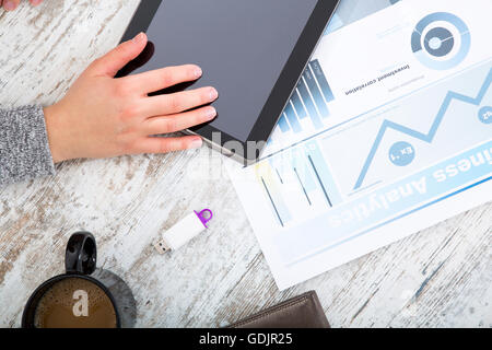 La main d'une femme à une table useing une tablette. Banque D'Images