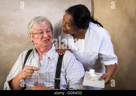 Grumpy Old grandpa en soins infirmiers accueil recevoir des médicaments par une infirmière Banque D'Images