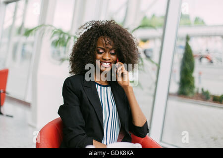 Belle vivacité young African American lady avec afro hairstyle chatter sur son mobile à l'écoute téléphonique, large sourire rayonnant de joie Banque D'Images