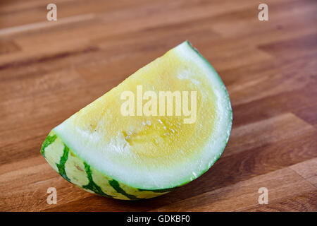 Tranche de melon jaune, allongé sur une table de bois stratifié brun foncé Banque D'Images