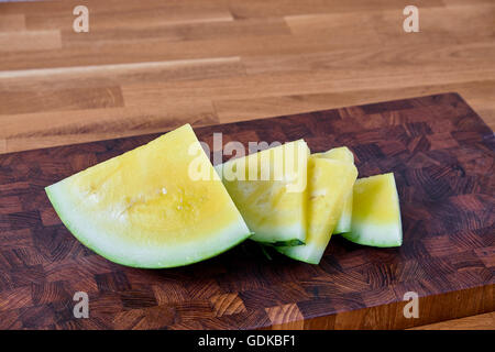 Tranche de melon jaune, allongé sur une table de bois stratifié brun foncé Banque D'Images