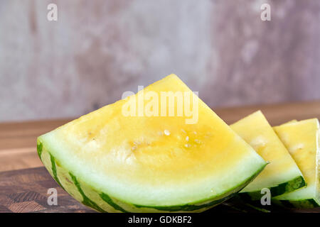 Tranche de melon jaune, allongé sur une table de bois stratifié brun foncé Banque D'Images