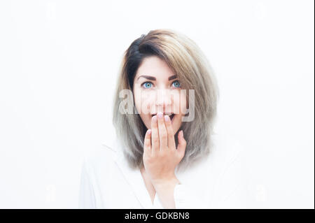 Jeune femme blonde yeux bleu expression étonné isolé sur blanc portrait Banque D'Images