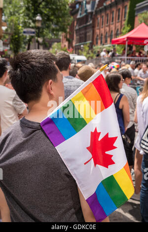 Toronto, Canada - le 3 juillet 2016 : Un spectateur mâle est à regarder la parade de la gay pride, tenant un drapeau arc-en-ciel Canada gay Banque D'Images
