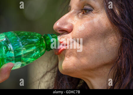 Close up of young woman ménopause l'eau potable à partir d'une bouteille en plastique Banque D'Images