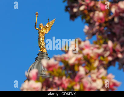 Ange de l'illumination, statue sur le dessus de l'édifice à travers les magnifiques magnolia fleurs au printemps Banque D'Images