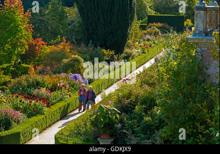 Vue plongeante sur les jardins à travers le chemin d'été avec des frontières et des haies basses avec couple en train de marcher sur le gravier Banque D'Images