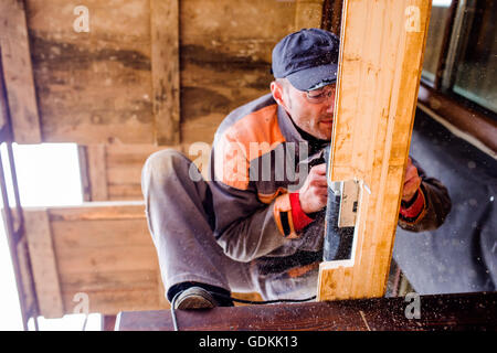 L'homme le meulage des planches de bois pour la construction domiciliaire. Banque D'Images