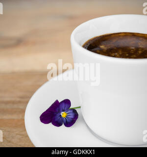 Tasse de café expresso avec des fleurs disposées sur la vieille table en bois rustique Banque D'Images