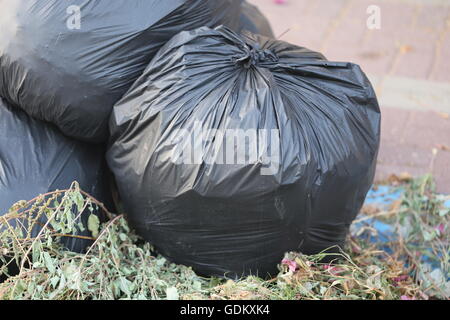 Plein de sacs à déchets. Pile de sacs à déchets vert attaché fermement, placé sur le sol dans la rue. Banque D'Images