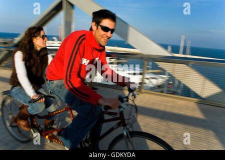 Deux amis équitation pont en tandem sur Yacht club et de la marina, de la zone du Forum, Barcelone, Espagne Banque D'Images