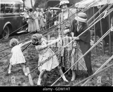 Cette charmante photo, prise à l'Abergeldie Château (Ecosse) Fete, derrière le chapiteau dans lequel les deux petites princesses vendu white heather à l'aide des fonds de l'église de Crathie. La princesse Elizabeth profite d'une lutte à la corde avec un ressort de Heather, alors que la princesse Margaret Rose joue avec les cordes. Banque D'Images