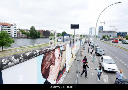 Les touristes sont à la peinture 'baiser fraternel entre Leonid Breschnew et Erich Honecker" (également appelé "Mon Dieu, aide-moi à survivre à cette terrible Love') par Dmitri Wladimirowitsch Wrubel à la East Side Gallery à Berlin, Allemagne, 19 juillet 2016. Depuis quelques mois, le monument situé sur l'ancienne frontière allemande-intérieur a été réparé et rénové en raison de nombreuses smearings sur l'œuvre. La clôture a pour but de protéger la peinture de l'endommagement par renouvelé des visiteurs. Le bureau de l'administration locale des plans de Friedrichshain-Kreuzberg continue de protéger l'œuvre même après les travaux de rénovation. Photo Banque D'Images