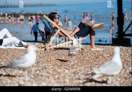 Un homme aime le temps chaud sur la plage de Brighton, comme une mini vague de températures les plus chaudes apporte de l'année. Banque D'Images