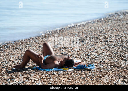 Un homme aime le temps chaud sur la plage de Brighton, comme une mini vague de températures les plus chaudes apporte de l'année. Banque D'Images