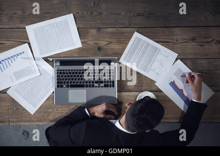 Businessman working on laptop avec les documents financiers, vue d'en haut Banque D'Images