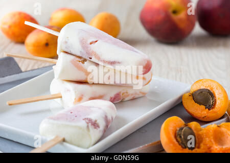 Des pêche abricot et orange les sucettes glacées sur plaque blanche avec fruits frais, été traite Banque D'Images
