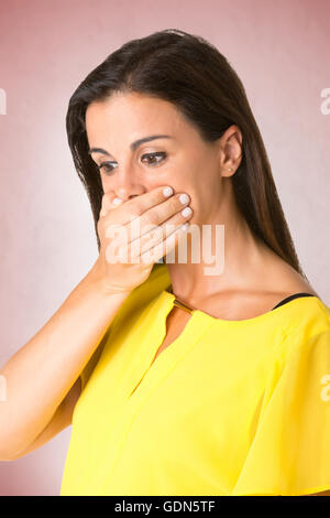 Surpris femme couvrant sa bouche, dans un fond rouge Banque D'Images