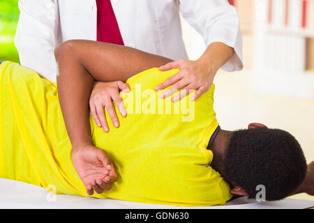 L'homme couché s'épaule de traitement physique physio-thérapeute, patient à la caméra dans ses mains tout en travaillant sur son bras, concept médical Banque D'Images