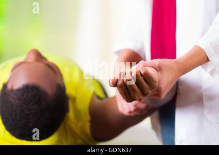 L'homme couché s'épaule de traitement physique physio-thérapeute, patient à la caméra dans ses mains tout en travaillant sur son bras, concept médical Banque D'Images