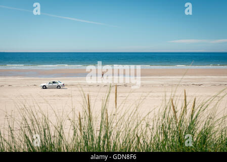 Ireland Beach Inch Strand et homme solitaire jogging et voiture sur une plage à Inch Beach, comté de Kerry, Irlande Banque D'Images